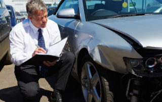 Seven Secret Tactics Car Insurance Claim Adjusters Use to Reduce Your Claim - man assessing a car wreck damage
