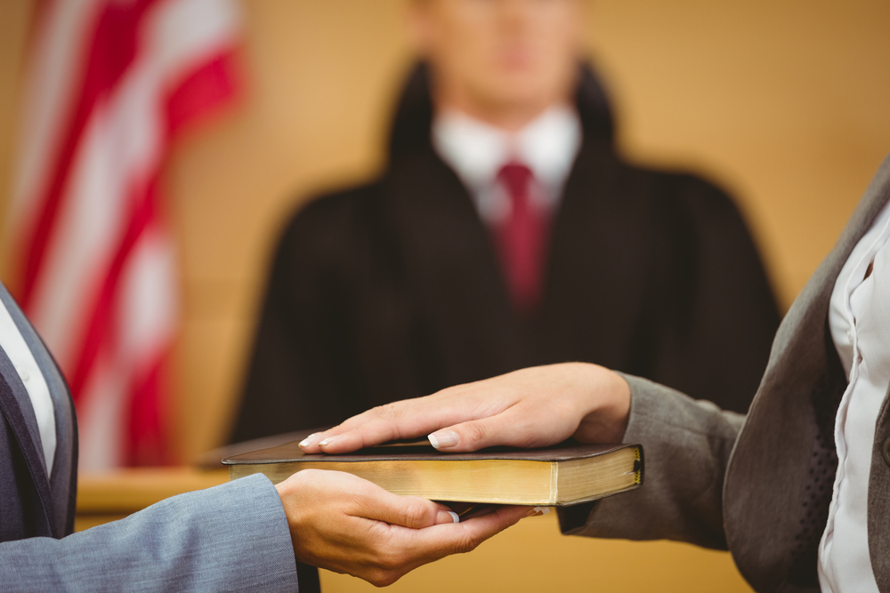 Witness in court swearing with and over Bible - Witnesses In Deposition
